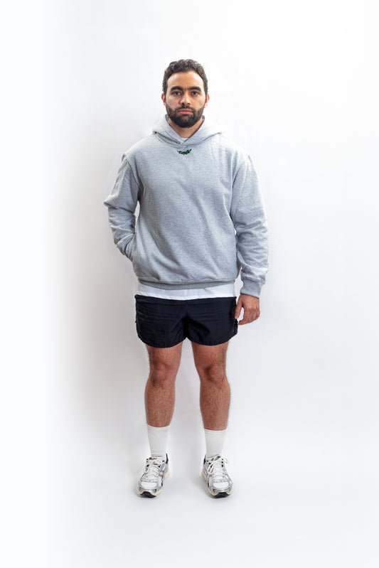 An athletic individual donning a heavyweight grey hoodie adorned with the Sartorial Athletics logo in the front, showcasing its versatile blend of sartorial quality and athletic aesthetics. Elevate your casual, vintage, or aesthetic outfits effortlessly with this premium-quality hoodie from Sartorial Athletics