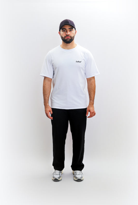A classic outfit featuring essential basics: a crisp white t-shirt paired with sleek black chinos, topped with a navy blue cap for a touch of flair.